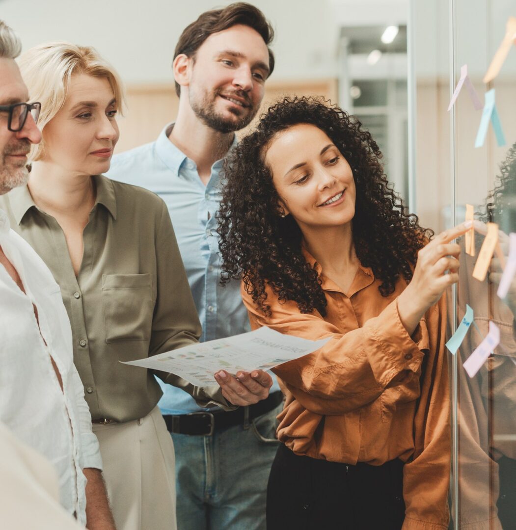 GettyImages-1730967605 Team collaborating with sticky notes on glass.